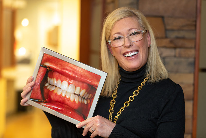 Patient Chandra holding up her before and after